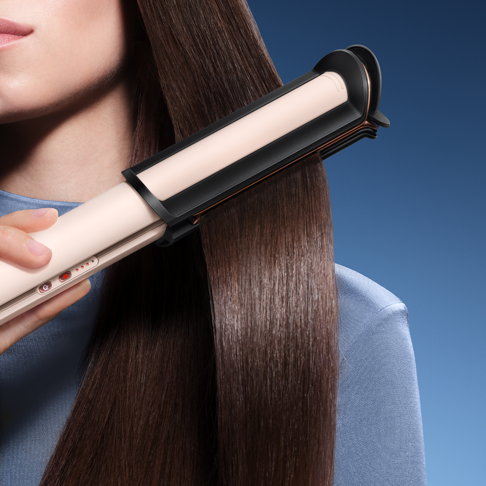 žena žehlící pramen vlasů za pomoci žehličky na vlasy Dyson Corrale CoolShine (Ceramic pink / Rose gold)