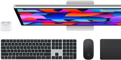 Kolekce příslušenství a zařízení včetně AirPodů, Magic Keyboardu s Touch ID, Magic Mouse, Magic Trackpadu a Studio Displaye