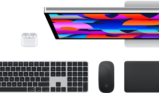 Kolekce příslušenství a zařízení včetně AirPodů, Magic Keyboardu s Touch ID, Magic Mouse, Magic Trackpadu a Studio Displaye