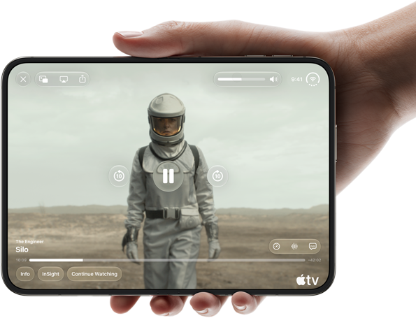 Úplně otevřený iPhone Duo, jedna ruka ho drží na šířku, na vnitřní obrazovce je snímek ze seriálu Apple TV „Silo“